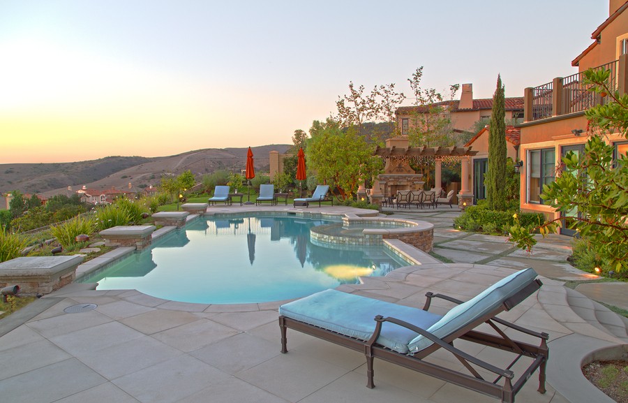 A large home with a backyard with a pool overlooking the hillside.