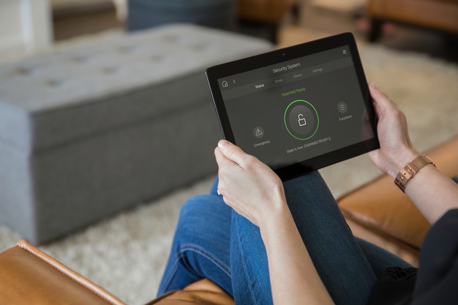 A woman arms the alarm system in her home on a home automation control tablet. 