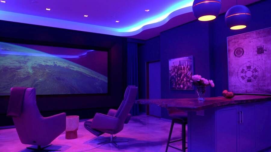 A modern media room illuminated by purple lighting.