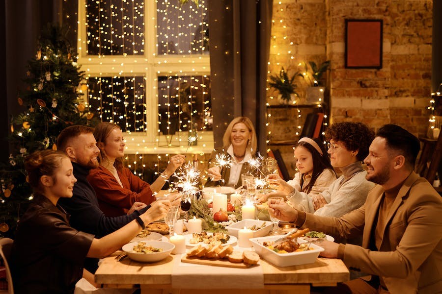 A happy family has Christmas dinner together while they light sparklers.